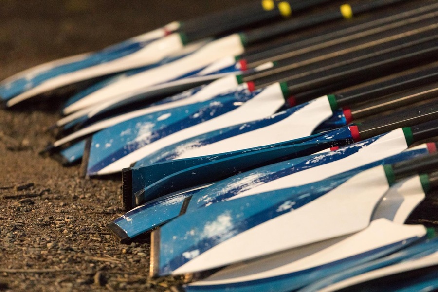 Blue and white striped rowing oars on the ground