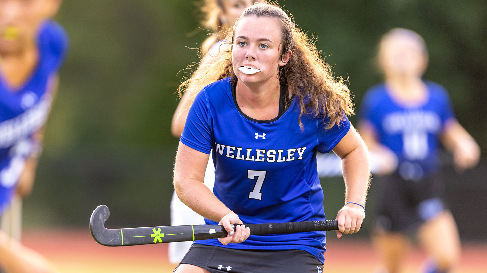 field hockey player with stick in Blue Wellesley jersey